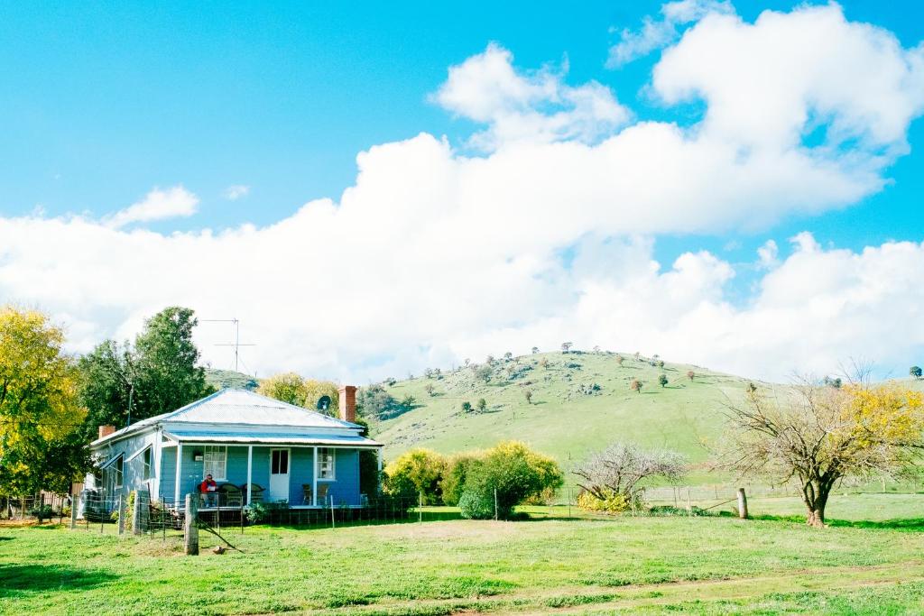 a blue house in a field with a hill in the background at Kimo Estate in Gundagai