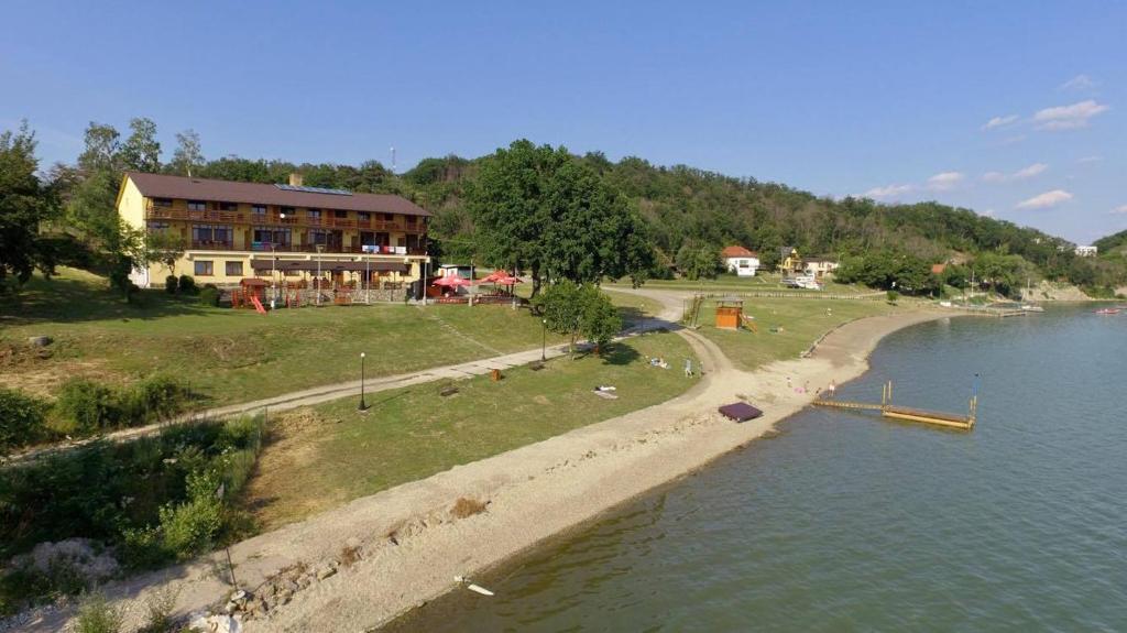 a house on the shore of a river with a building at Penzión Anima in Kaluža