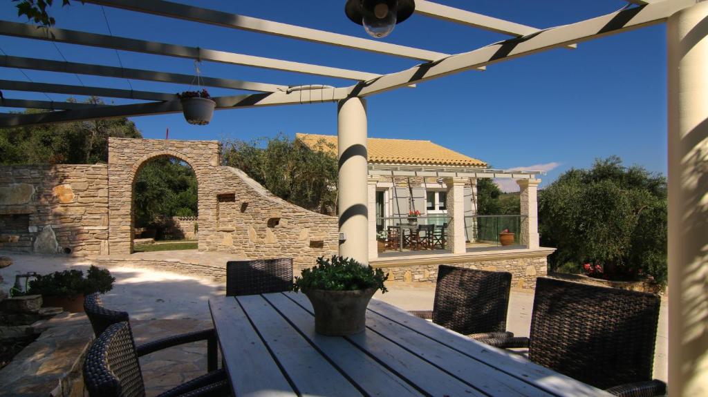 a wooden table and chairs on a patio with a gazebo at Villa Ellie in Agios Stefanos