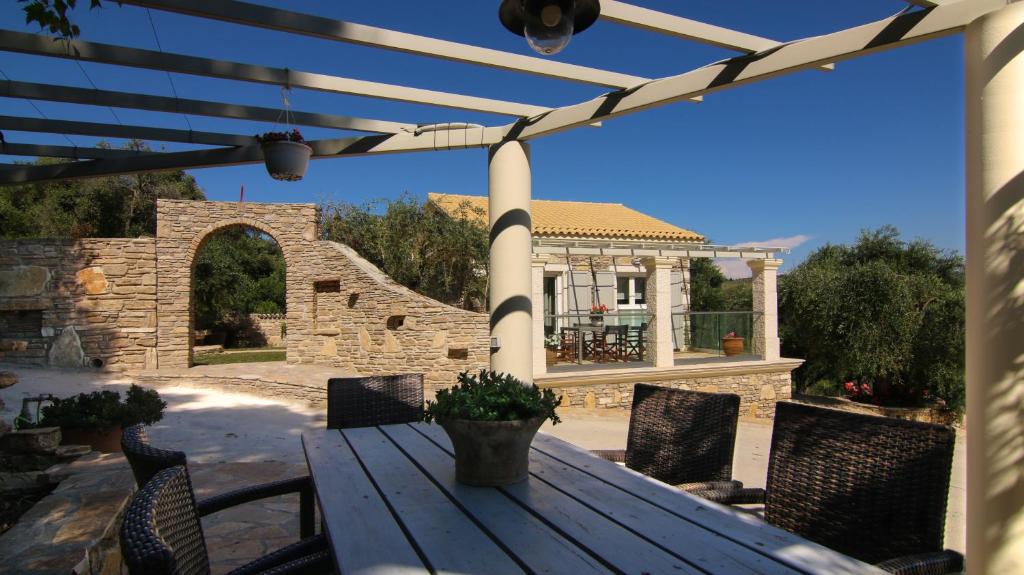 drewniany stół i krzesła na patio z altaną w obiekcie Villa Ellie w mieście Agios Stefanos