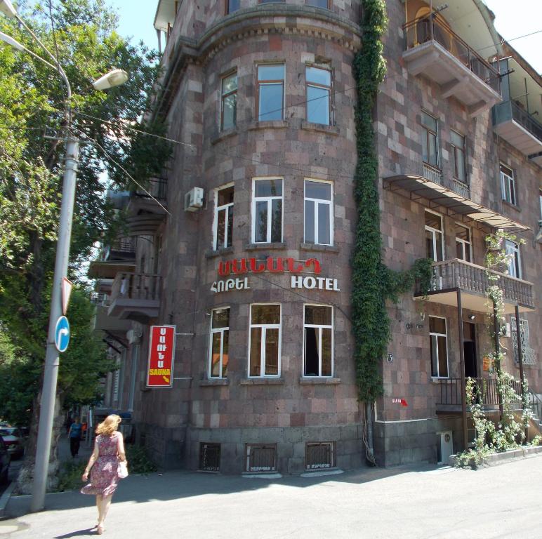 Una donna che cammina davanti a un edificio di mattoni di Manand Hotel a Yerevan