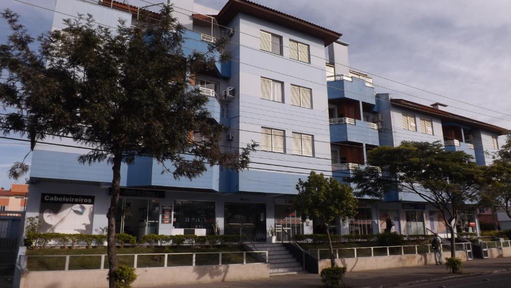 un edificio azul con un árbol delante de él en Residencial Camila Av das Nações, en Florianópolis
