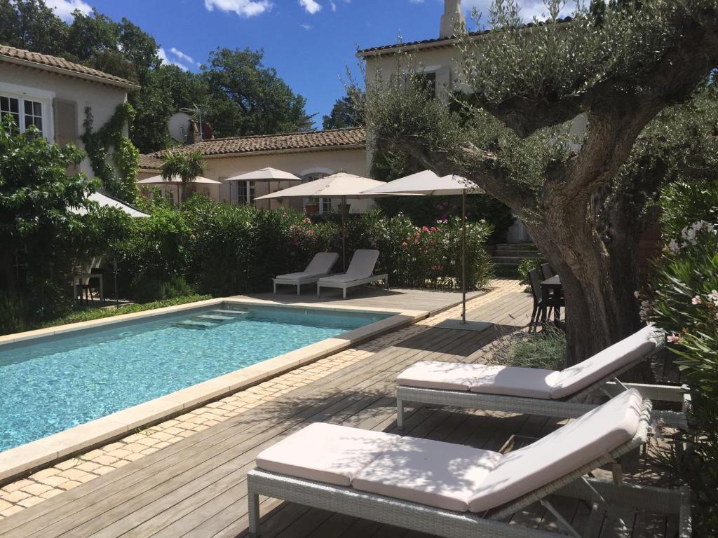 a swimming pool with chairs and a tree next to a house at Villa La Begude in Saint-Tropez