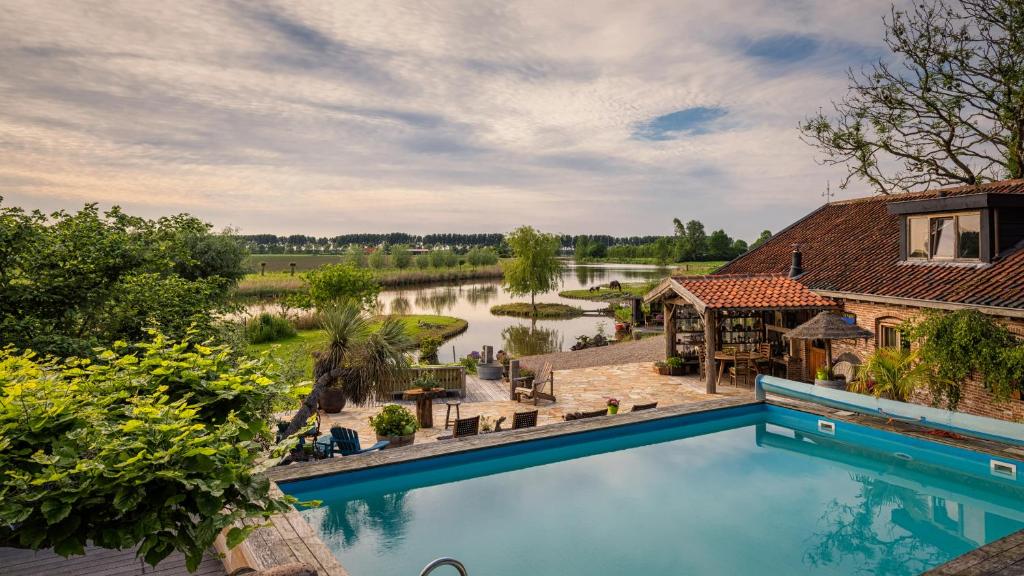 einem Luftblick auf ein Haus mit einem Pool und einem Fluss in der Unterkunft Guesthouse Ensenada in Schoondijke