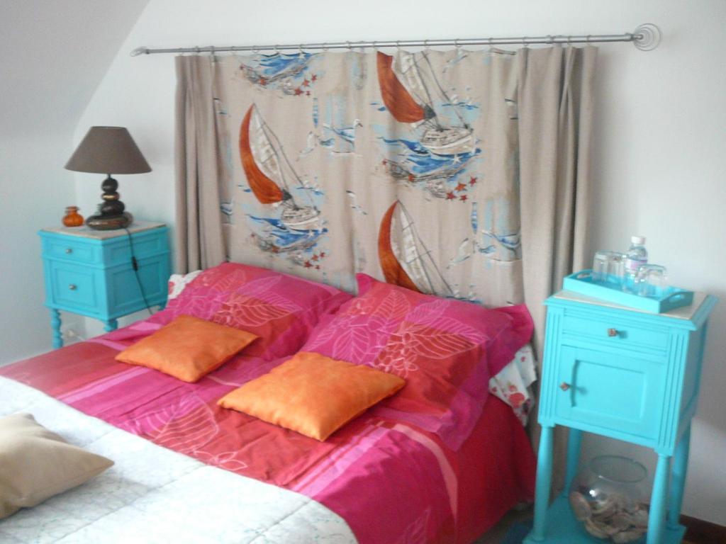 - une chambre avec un lit doté de draps roses et d'oreillers orange dans l'établissement Kerbarbo, à Plouagat