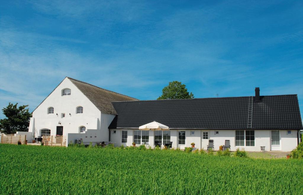a white barn with a black roof on a green field at Vallebergaslätt in Löderup