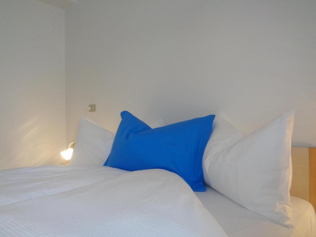 a blue pillow sitting on top of a white bed at Hotel Garni Suisse in San Martino di Castrozza