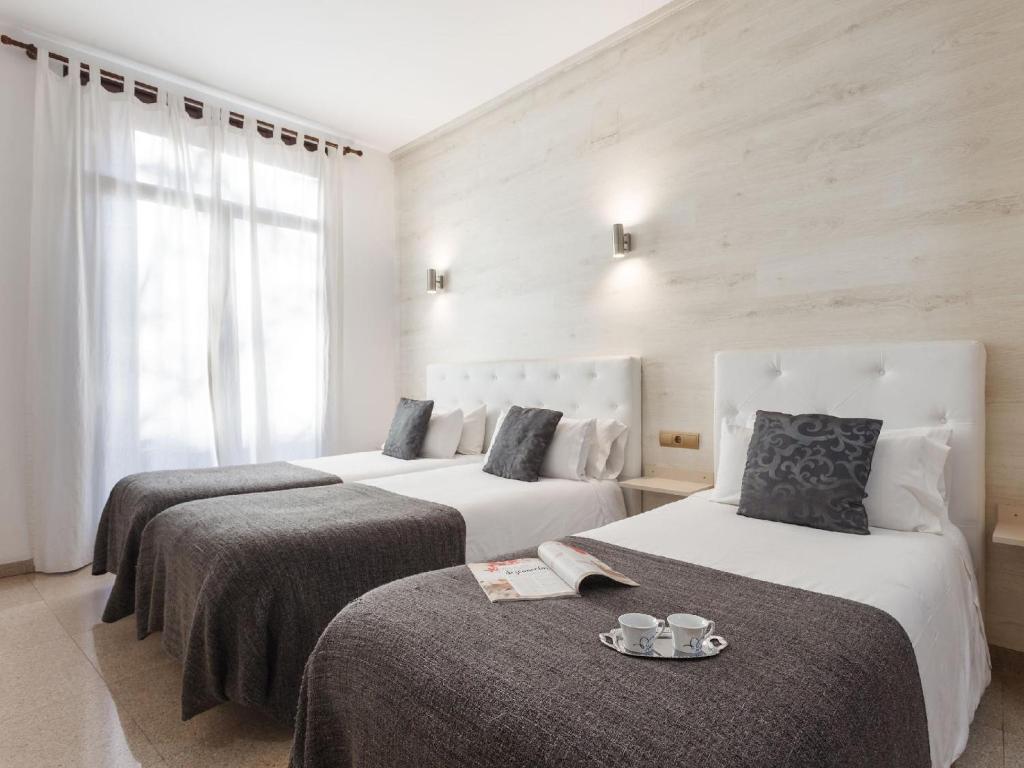 Dos camas en una habitación de hotel con dos tazas. en Aparthotel Rambla108 en Barcelona