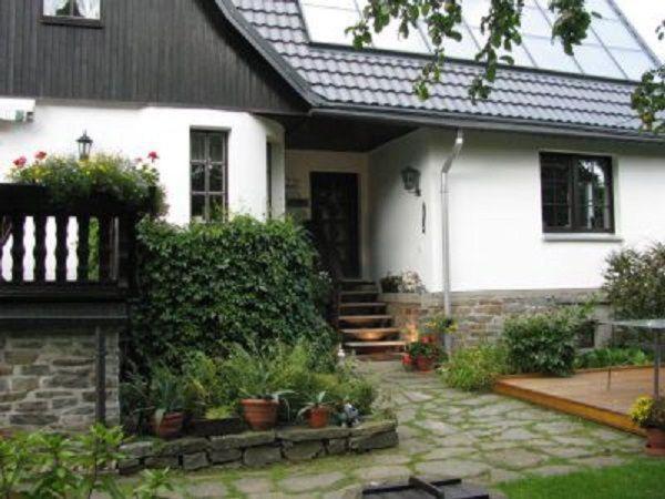 ein weißes Haus mit einer Veranda mit Topfpflanzen in der Unterkunft Ferienhaus Landmann in Tannenberg