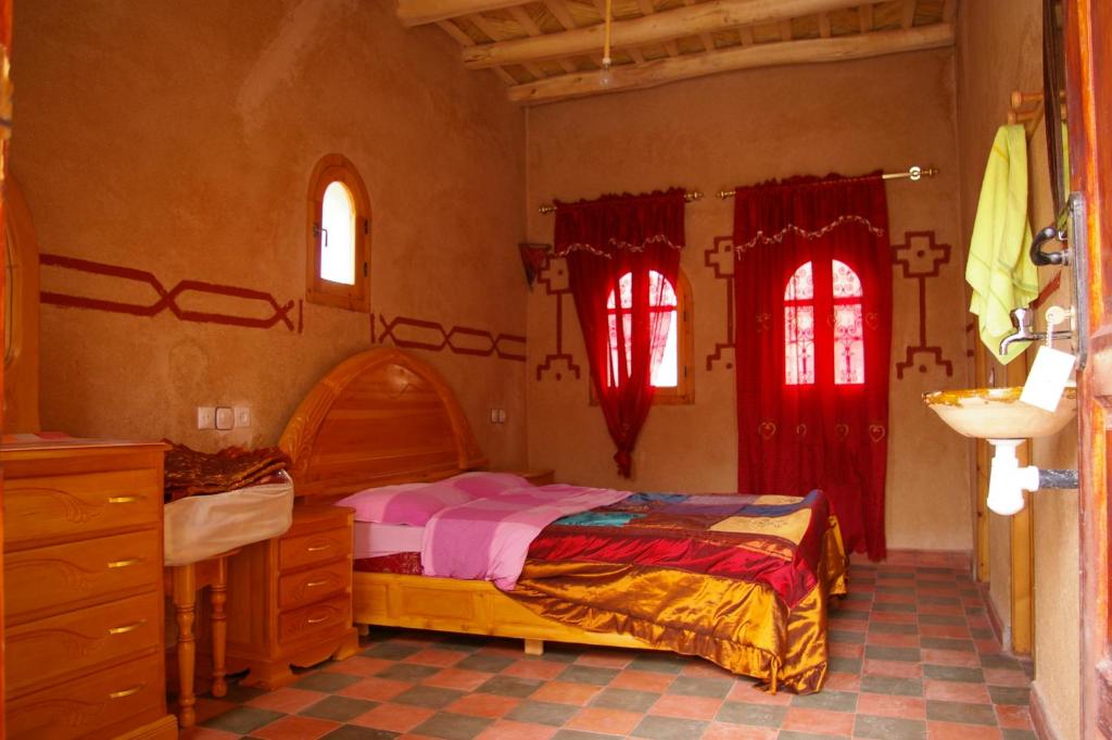a bedroom with a bed and two windows at Auberge Des Jardins du Dades in Boumalne Dades