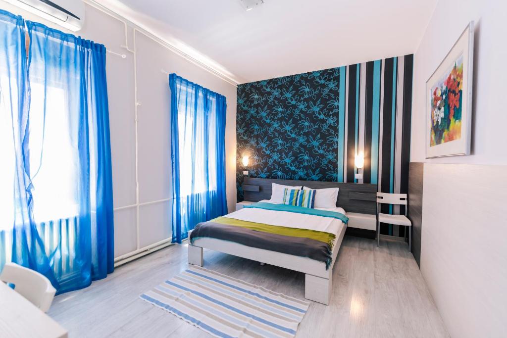 um quarto com uma cama com cortinas azuis em Garni Citi Hotel Veliki em Novi Sad