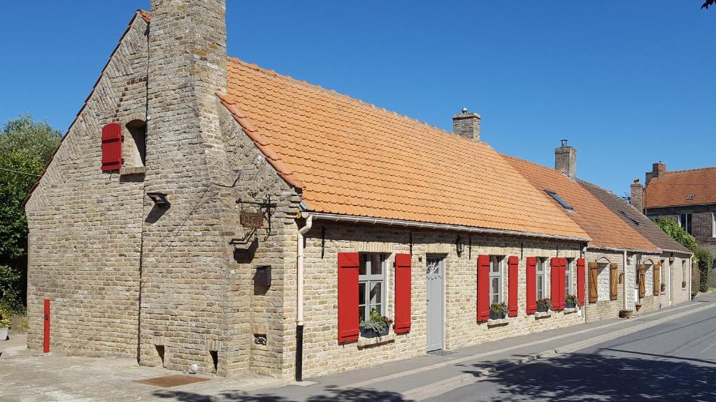 um velho edifício de tijolos com persianas vermelhas numa rua em Chambres d'hôtes du chemin de la maison blanche em West-Cappel