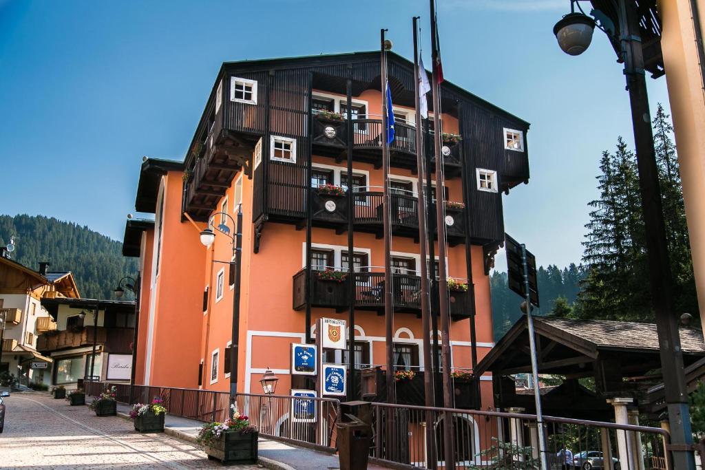 a tall orange building with balconies on a street at Hotel Posta R.T.A. in Madonna di Campiglio