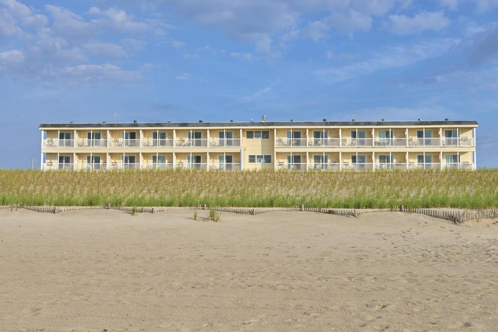 a building on the beach next to the beach at Drifting Sands Oceanfront Hotel in Ship Bottom