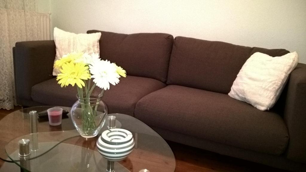 a living room with a couch and a glass table with flowers at Enipeas Apartment in Litochoro