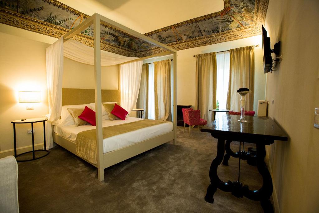 a bedroom with a canopy bed and a table at Palazzo Franceschini in Cascia