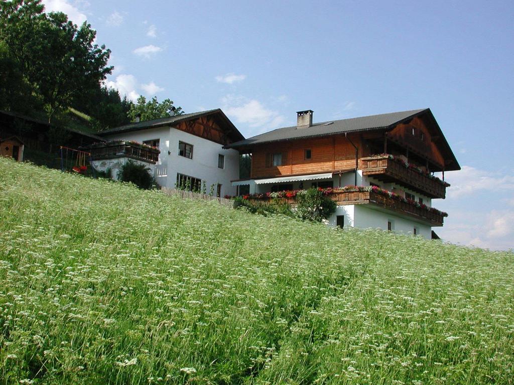 un bâtiment au sommet d'une colline avec un champ d'herbe dans l'établissement Zehrehof, à Bressanone