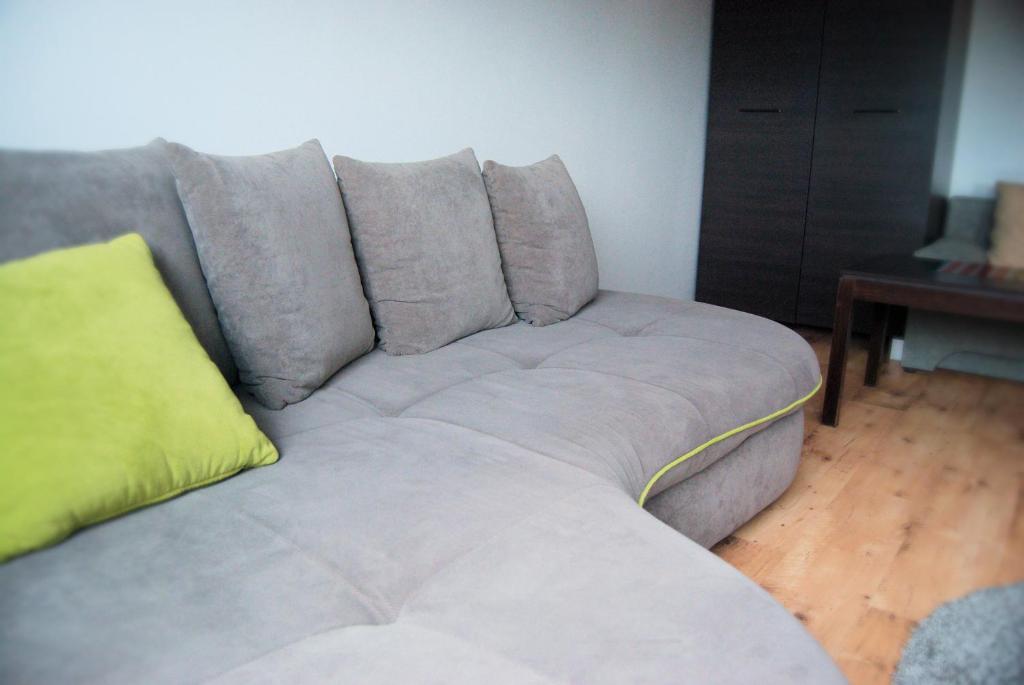 a gray couch with a yellow pillow on it at Apartament u Teofila in Koszalin