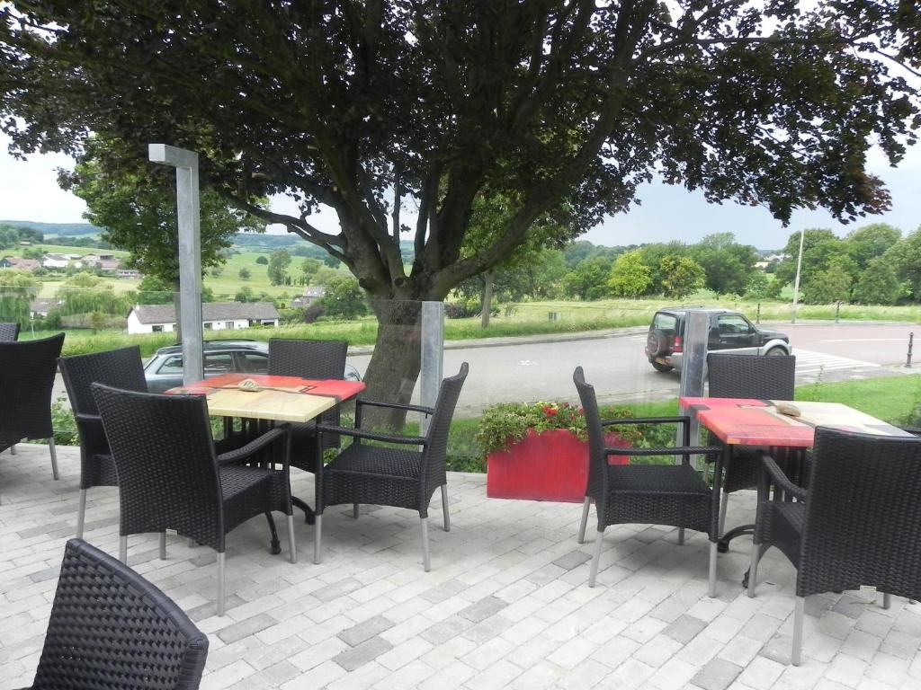 um pátio com mesas, cadeiras e uma árvore em Hotel - Restaurant Uit De Kunst em Vijlen