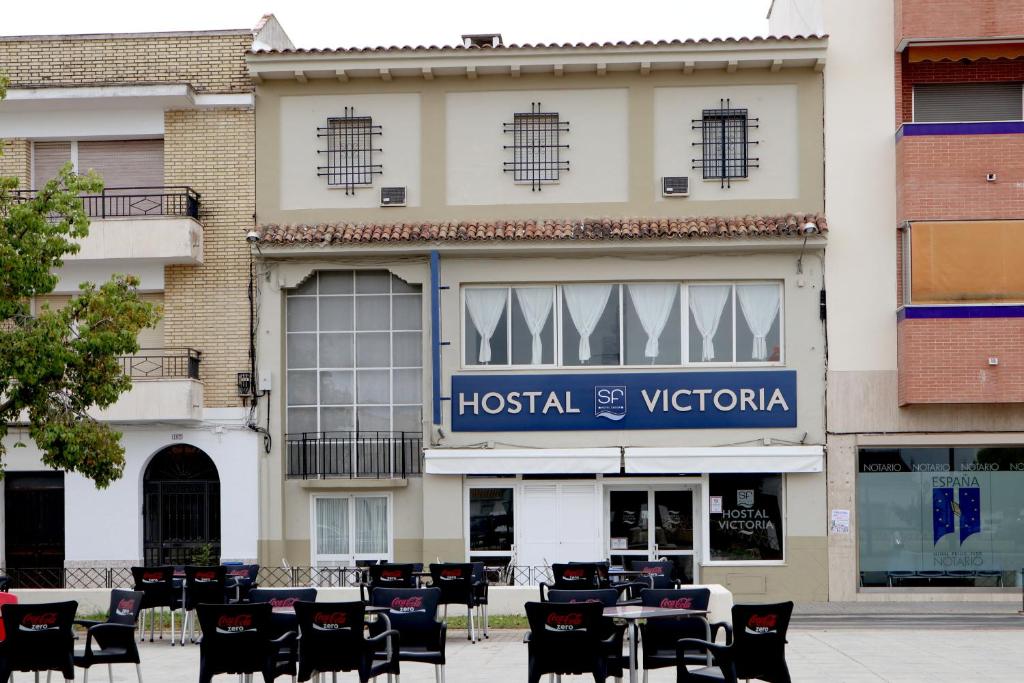 a hotel with tables and chairs in front of a building at Hostal Victoria in La Carlota