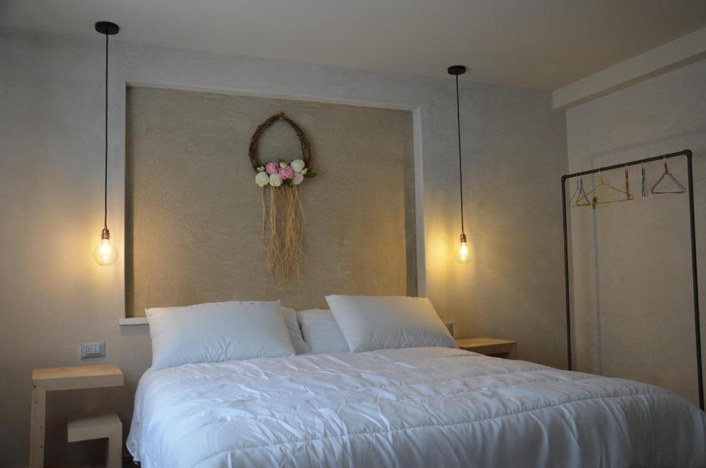 B&B Vicolo15 في بييفي دي كادوري: غرفة نوم مع سرير أبيض مع زهور على الحائط