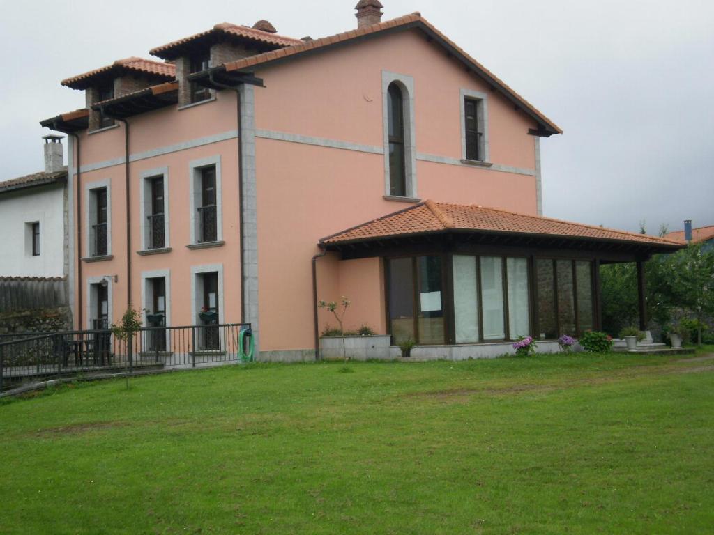 Quintana de LlanesにあるApartamentos Rurales Villa Carlaの芝生の庭のある大きなピンクの家