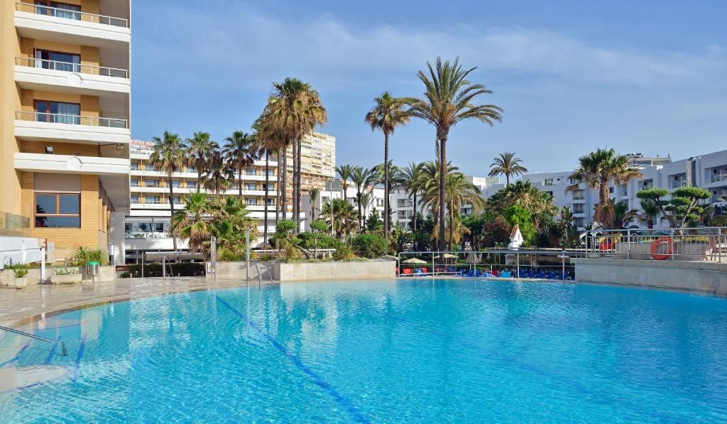 ein großer Pool mit Palmen und Gebäuden in der Unterkunft Sol Torremolinos - Don Pablo in Torremolinos