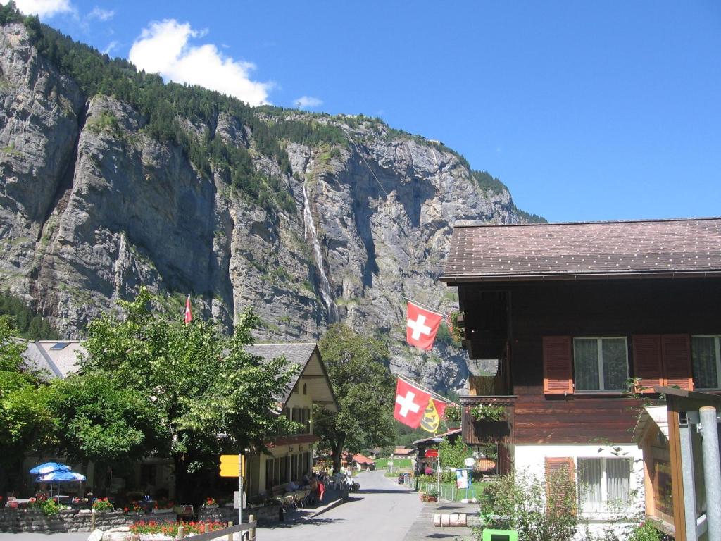 a mountain with two canadian flags in front of a building at Hotel-Restaurant Stechelberg Bed & Breakfast in Stechelberg