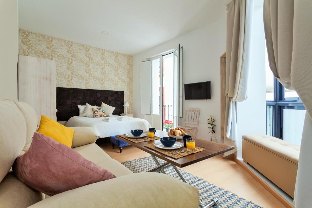 a living room with a bed and a couch at Hostly Acetres 1A loft in city center, comunal terrace, fibre,parking optional in Seville