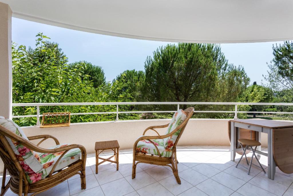 un patio avec deux chaises et une table sur un balcon dans l'établissement Les Jardins de Nazareth, à Montpellier