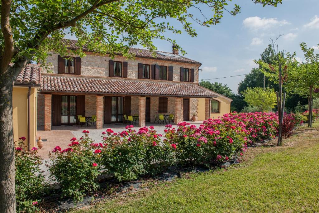 una casa con flores rosas delante de ella en Agriturismo La Vecchia Fonte, en Castelbellino