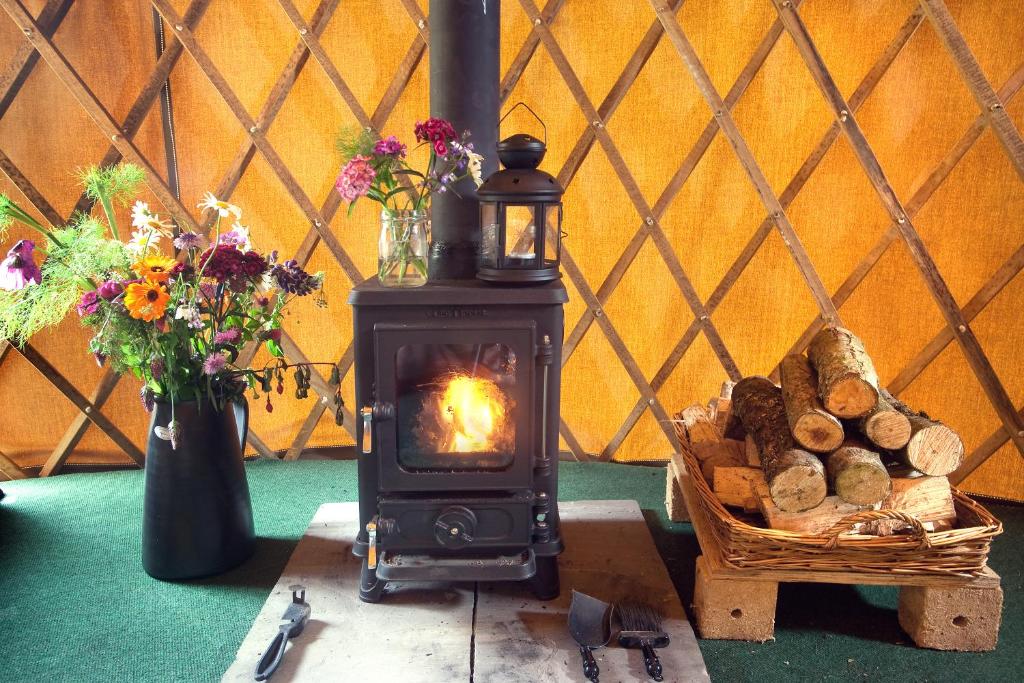 a wood burning stove with a basket of logs at Portsalon Luxury Camping in Portsalon