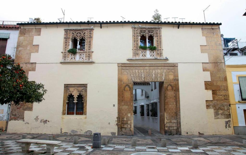 ein altes weißes Gebäude mit Fenstern und einem Tisch in der Unterkunft El Descanso del Indiano in Córdoba