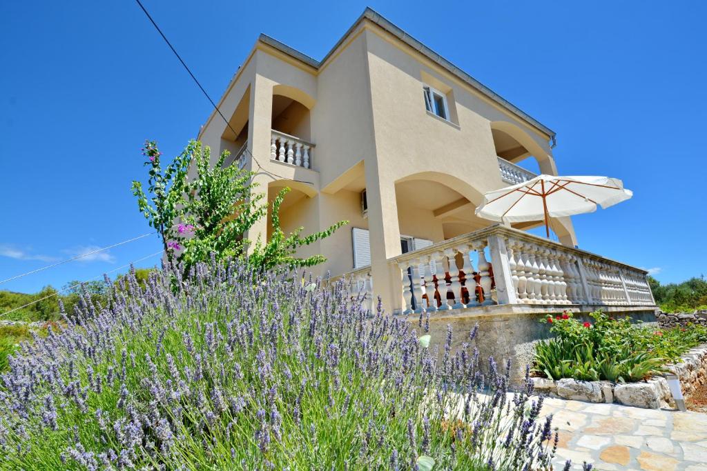 a house with purple flowers in front of it at Apartments Marta in Verunić