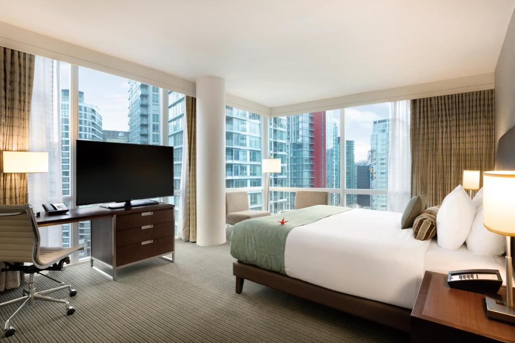 a hotel room with a large bed and a large window at Coast Coal Harbour Vancouver Hotel by APA in Vancouver