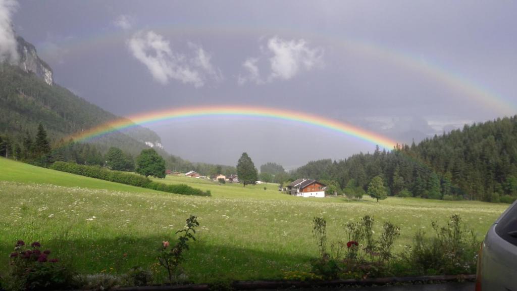 een regenboog in de lucht boven een groen veld bij Ferienwohnung Maurerhof in Sankt Johann in Tirol