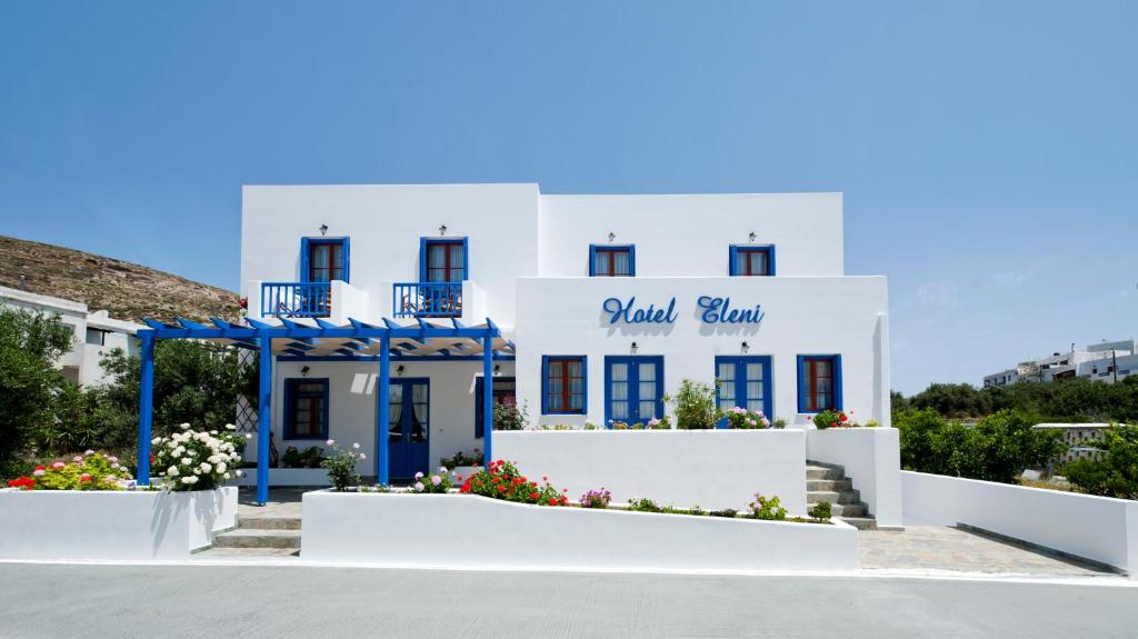 a white building with a blue sign on it at Hotel Eleni in Adamas