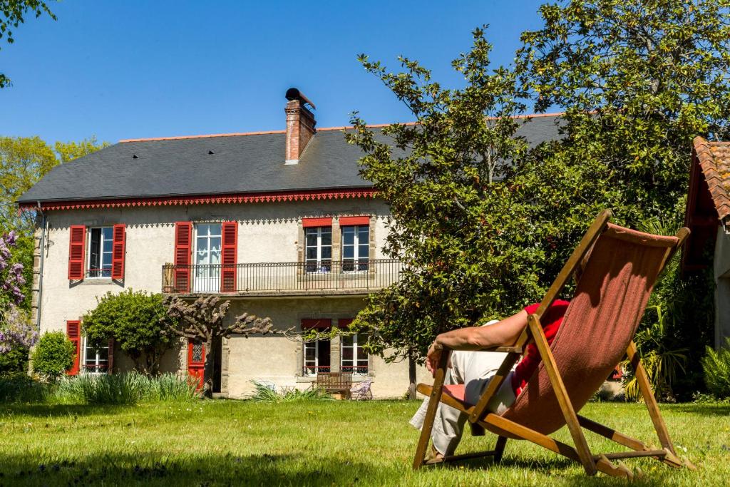 una persona sentada en una silla frente a una casa en La Maison de L'Ousse, en Livron