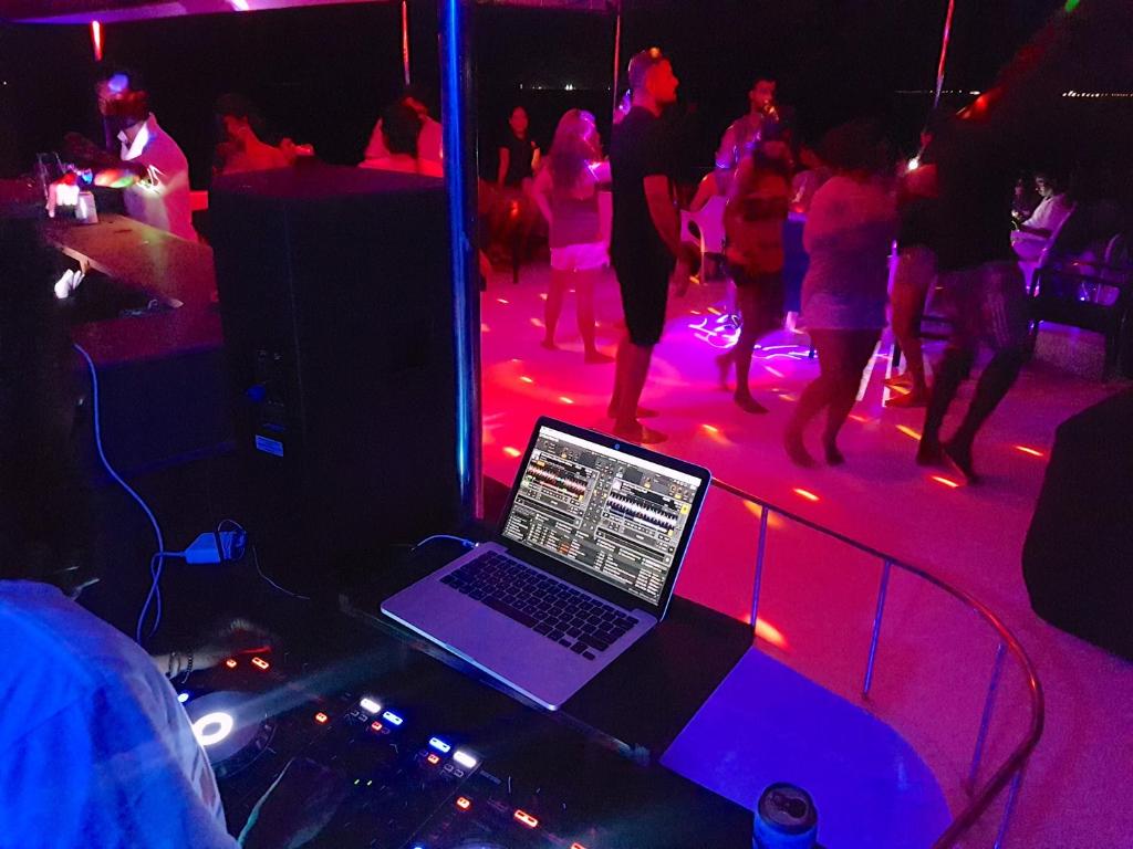 a laptop on a table in a nightclub with people dancing at Kaani Beach Hotel in Maafushi