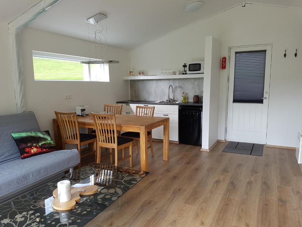 a living room with a table and a kitchen at Bólstaðarhlíð - Cottage (studio) in Bólstaðarhlíð