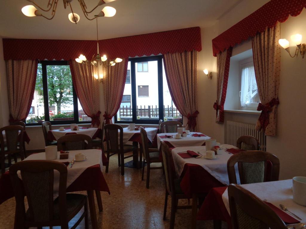 a dining room with tables and chairs and windows at Hotel Garni Suisse in San Martino di Castrozza