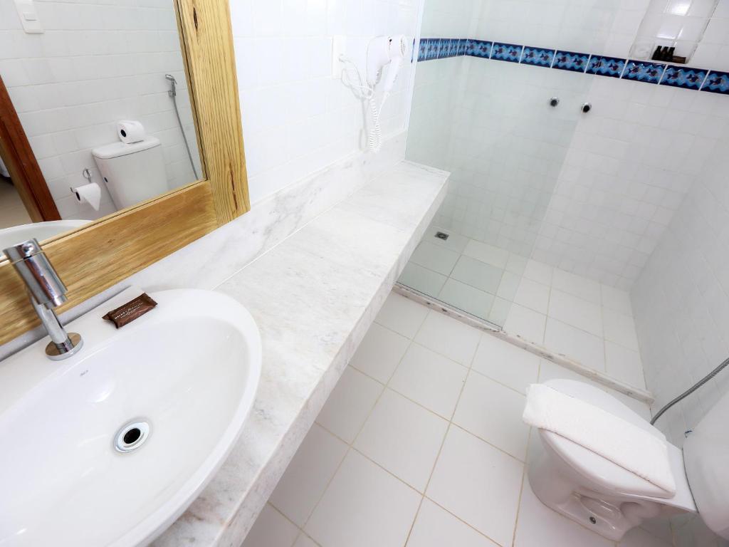a white bathroom with a sink and a toilet at Pousada Paraíso do Forte in Praia do Forte