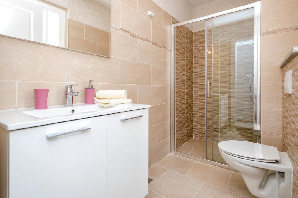 a bathroom with a toilet and a sink and a shower at Villa Riva in Jelsa