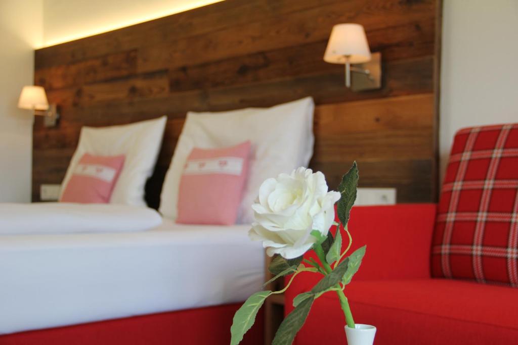 um quarto com uma cama e um sofá vermelho e uma flor em Landhaus Sommerau em Buchenberg