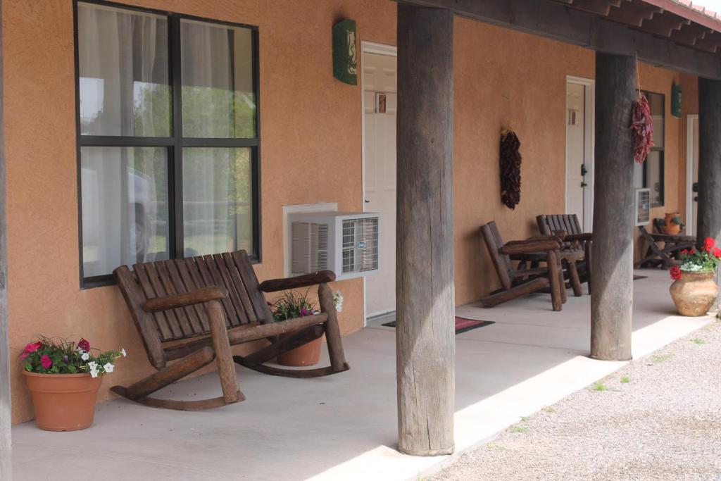 dwie drewniane ławki siedzące na boku budynku w obiekcie Adobe Rose Boutique Inn w mieście Artesia