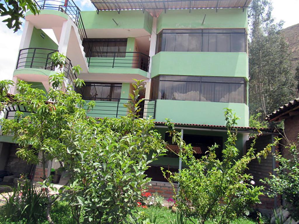 an apartment building with green balconies and trees at Hostal Ayllu in Urubamba