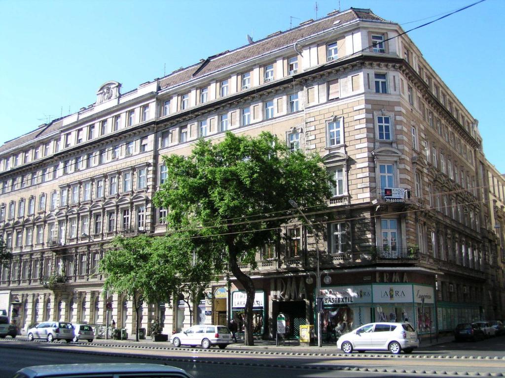 un gran edificio con coches estacionados frente a él en Eitans Guesthouse en Budapest