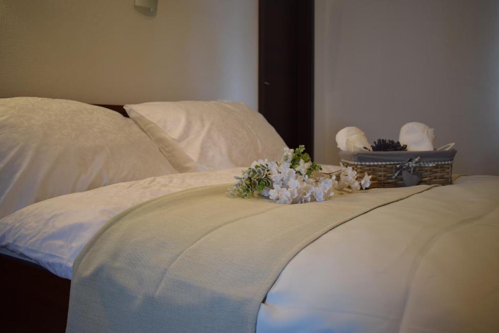 Saint Michael - Garni Hotel في ترنافا: سرير عليه شراشف بيضاء وزهور