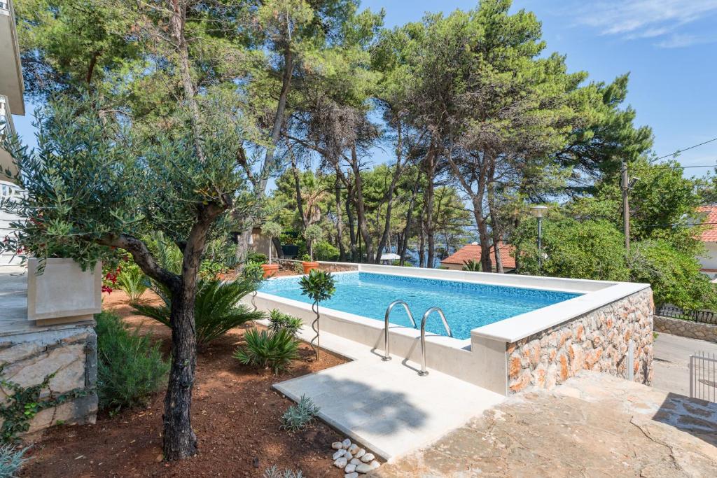 a swimming pool in a yard with a tree at Apartments Tamar in Jelsa