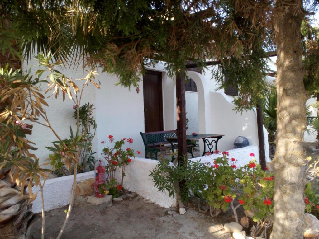 a house with a bench and some trees and flowers at Mar-Nik Village in Paliochori